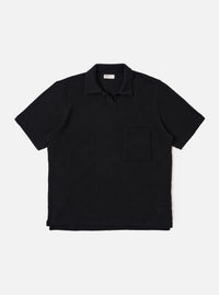 The Black Fantasy Checkerboard Vacation Polo is shown as a flat lay against a white background. The polo features an all-over black and grey checkerboard pattern, a one-piece open collar, a short buttonless placket, and a single patch pocket on the left chest. The short-sleeve garment has a stepped hem with side vents.