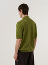 A model is wearing the Olive Cotton Lace Knit Jonny Knit Shirt, shown from the back against a plain white background. The shirt features a distinctive open lace-knit pattern throughout, a straight hem, and short sleeves. The model is wearing the olive green shirt over a light-colored top. No mannequin is present in the image.