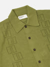The Olive Cotton Lace Knit Jonny Knit Shirt is shown from the back as a flat lay against a plain white background. The image highlights the fine 12-gauge knit and the openwork square lace pattern of the 100% cotton fabric. The short sleeves and straight hem are clearly visible.