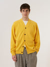 A model wears the Yellow Eco Cotton Knit Pocket David Cardigan against a plain white background. The knit cardigan features a V-neckline, a central button-down closure, and two large patch pockets at the waist. The vibrant yellow garment is shown in a front-facing view, highlighting its textured eco-cotton material.