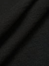 A close-up swatch of the Black Woolcot Bio S/S Pullover Knit Shirt II fabric highlights the smooth, fine-gauge texture of the black knit material. The image focuses on the blend of merino wool and organic cotton, with the fabric filling the entire frame.