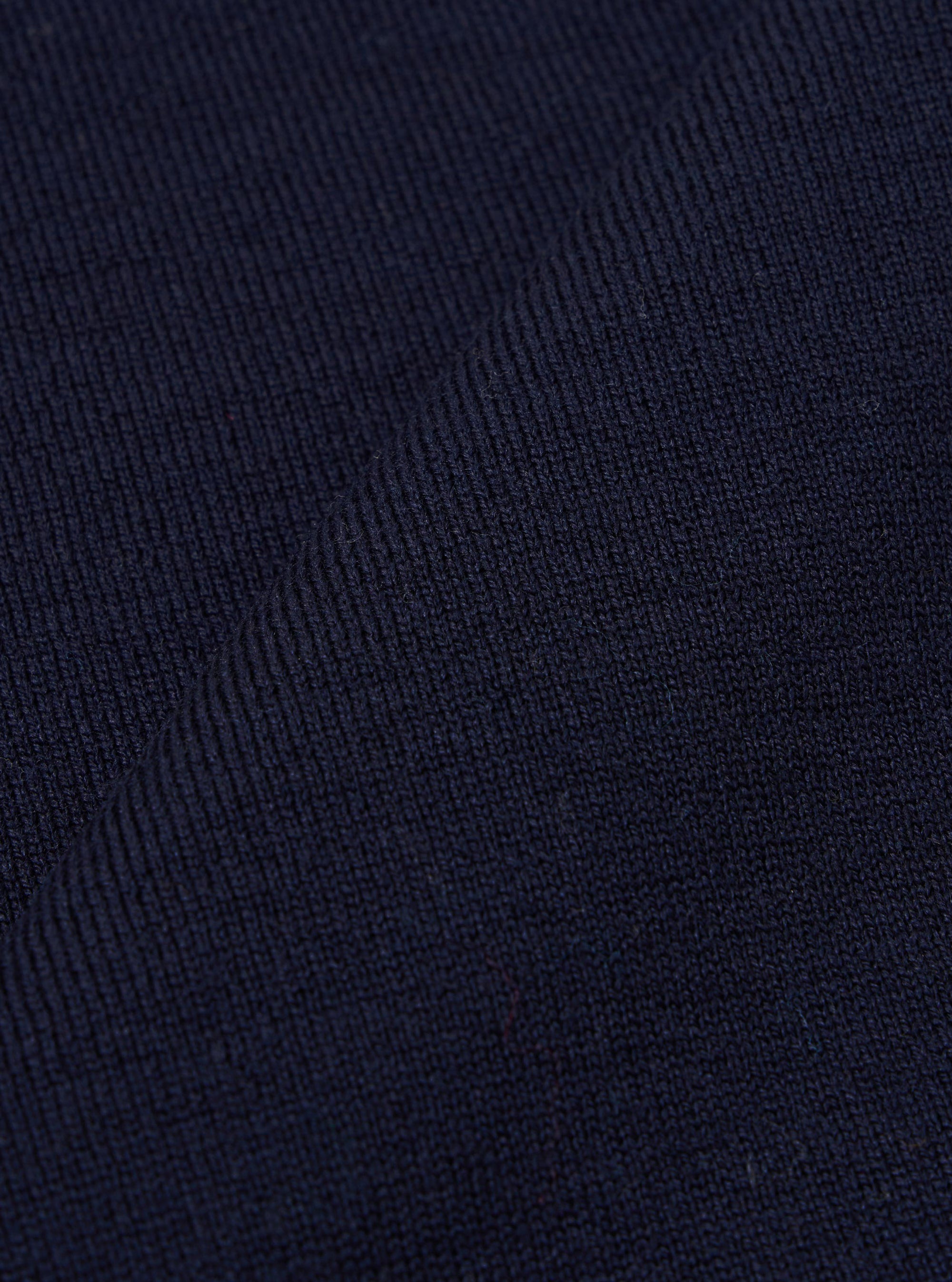 A close-up swatch image of the Navy Merino Fine Knit Knit Tee displays the detailed texture of the dark blue fabric. The fine-gauge knit pattern is the prominent feature of the image. No model or mannequin is present.