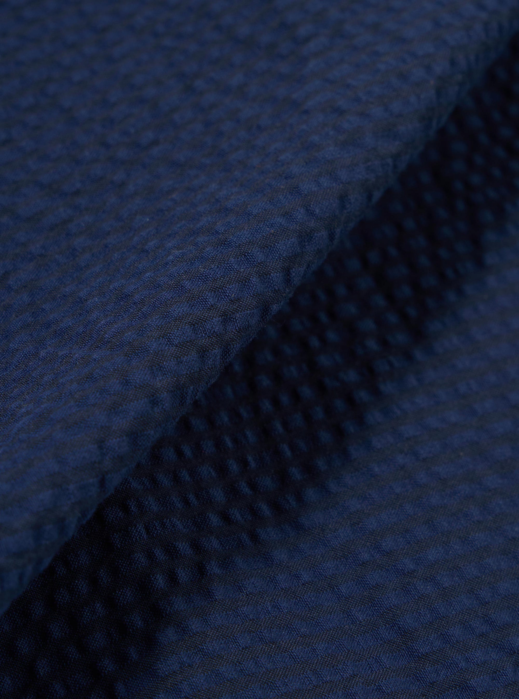 A close-up fabric swatch of the Navy Derby Stripe Clean Short highlights the vertical navy blue and white stripe pattern. The image provides a detailed view of the cotton fabric's weave and texture.