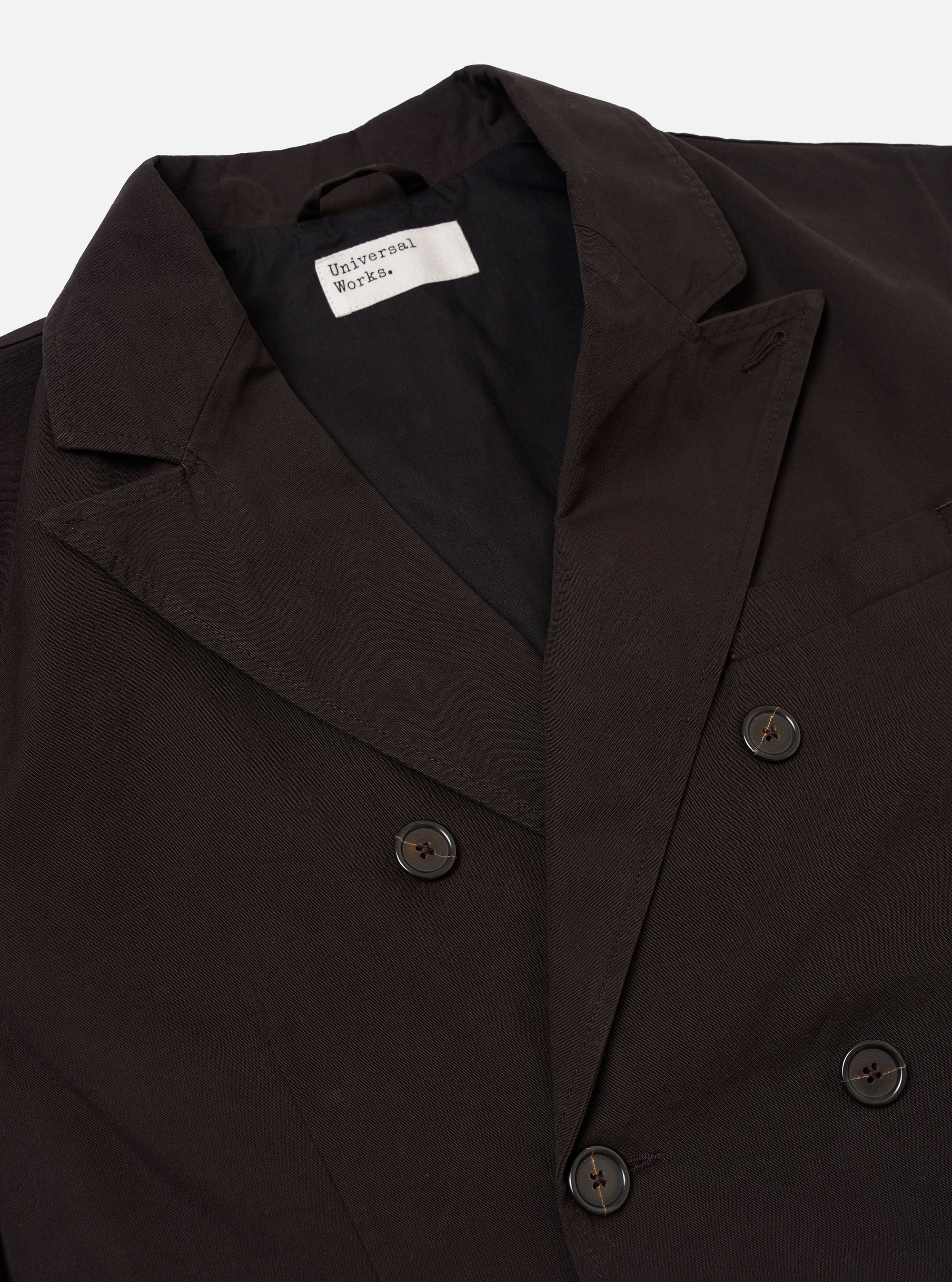The Licorice Summer Canvas Manor Jacket is shown from the back as a flat lay against a plain white background. The jacket features a clean rear panel with a straight hem and relaxed shoulders, characteristic of its casual suiting style. The dark brown canvas fabric is highlighted, showing a soft, suede-like texture.