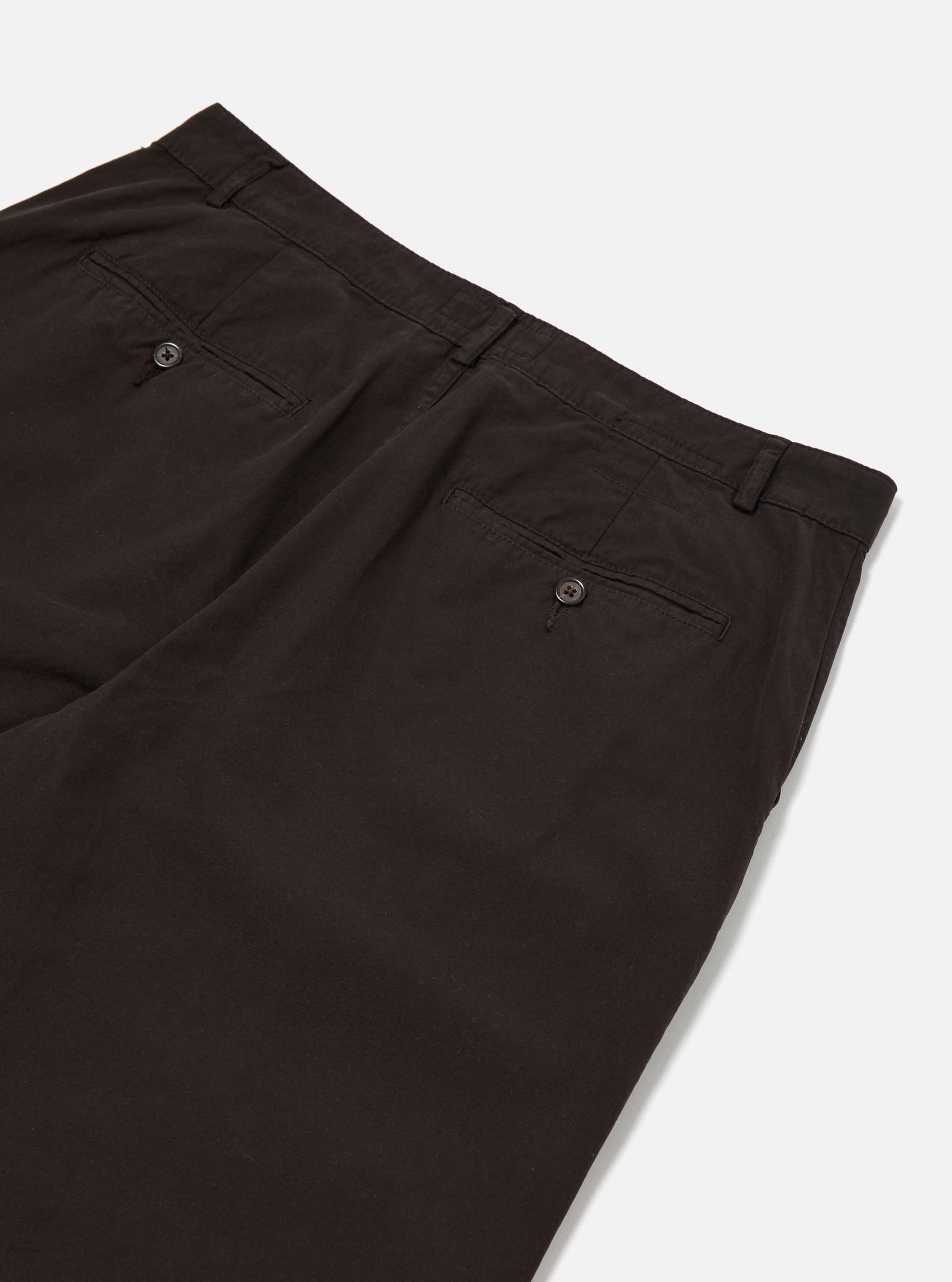 The Licorice Summer Canvas Military Chino is shown in a detail view as a flat lay against a plain white background. The image highlights the textured finish of the dark brown licorice-colored summer canvas fabric and the construction of the waistband and front pockets.