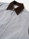 The Light Indigo Jean Cloth Reworked Rose Bowl Jacket is shown from the back as a flat lay against a plain white background. The image highlights the boxy fit, slightly oversized collar, and functional details including buttoned adjustable cuffs and an adjustable back hem with pleats. The light indigo organic cotton fabric features a clean, uniform finish.