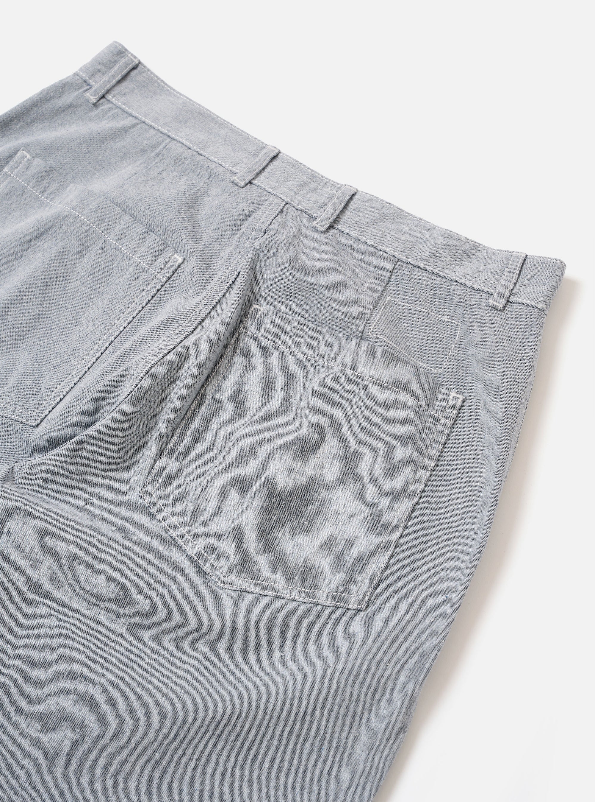 The Light Indigo Jean Cloth Reworked Duke Pant is shown from the back as a flat lay against a plain white background. The image highlights the two rear patch pockets and the wide-leg silhouette of the trousers. The light indigo organic cotton fabric features a textured, multi-tonal appearance.