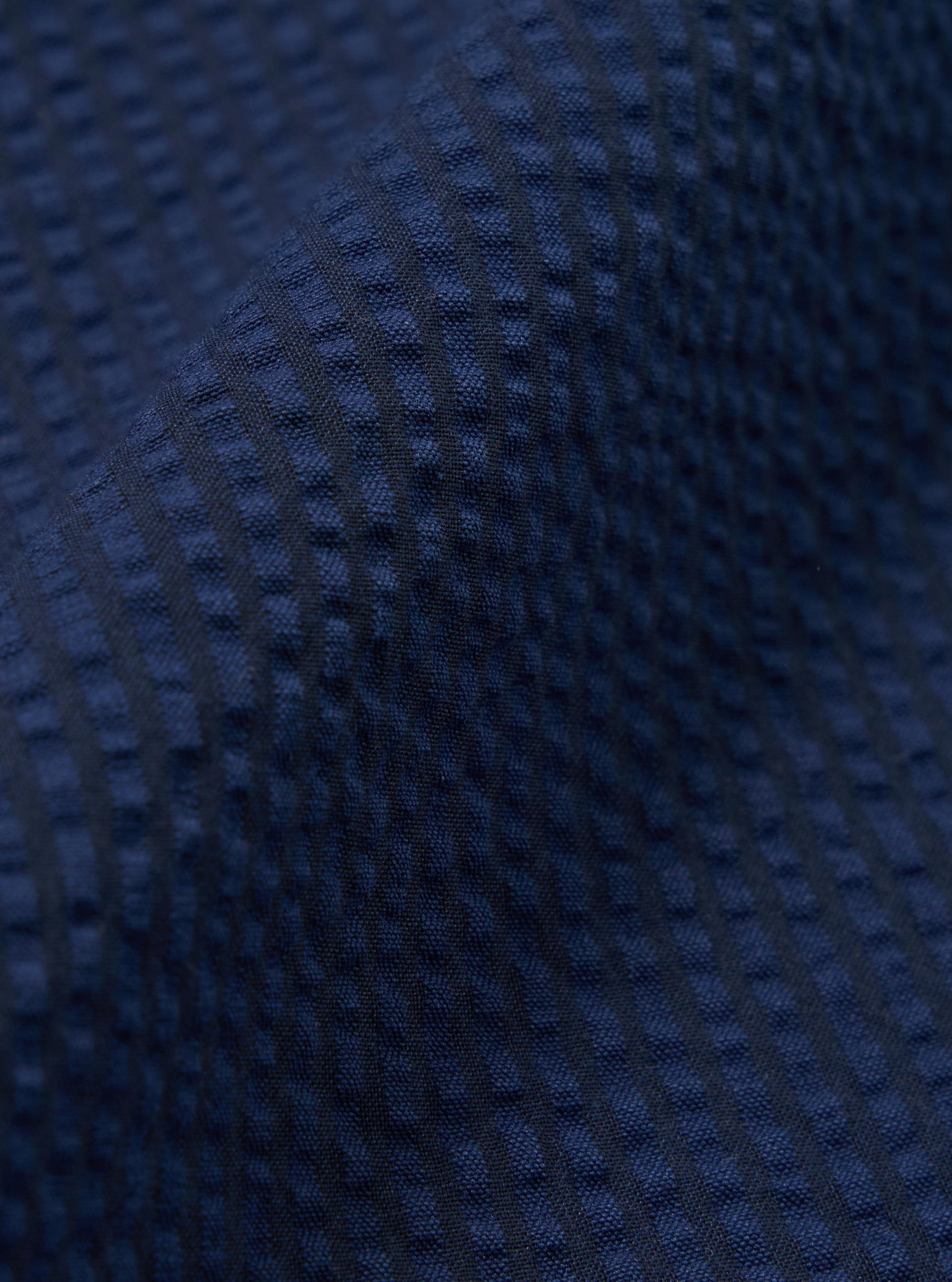 A close-up swatch image of the Navy Derby Stripe Oxford Pant fabric shows a pattern of thin, vertical navy blue and white stripes. The cotton material is the primary focus, highlighting the crisp texture and precise lines of the derby stripe design.