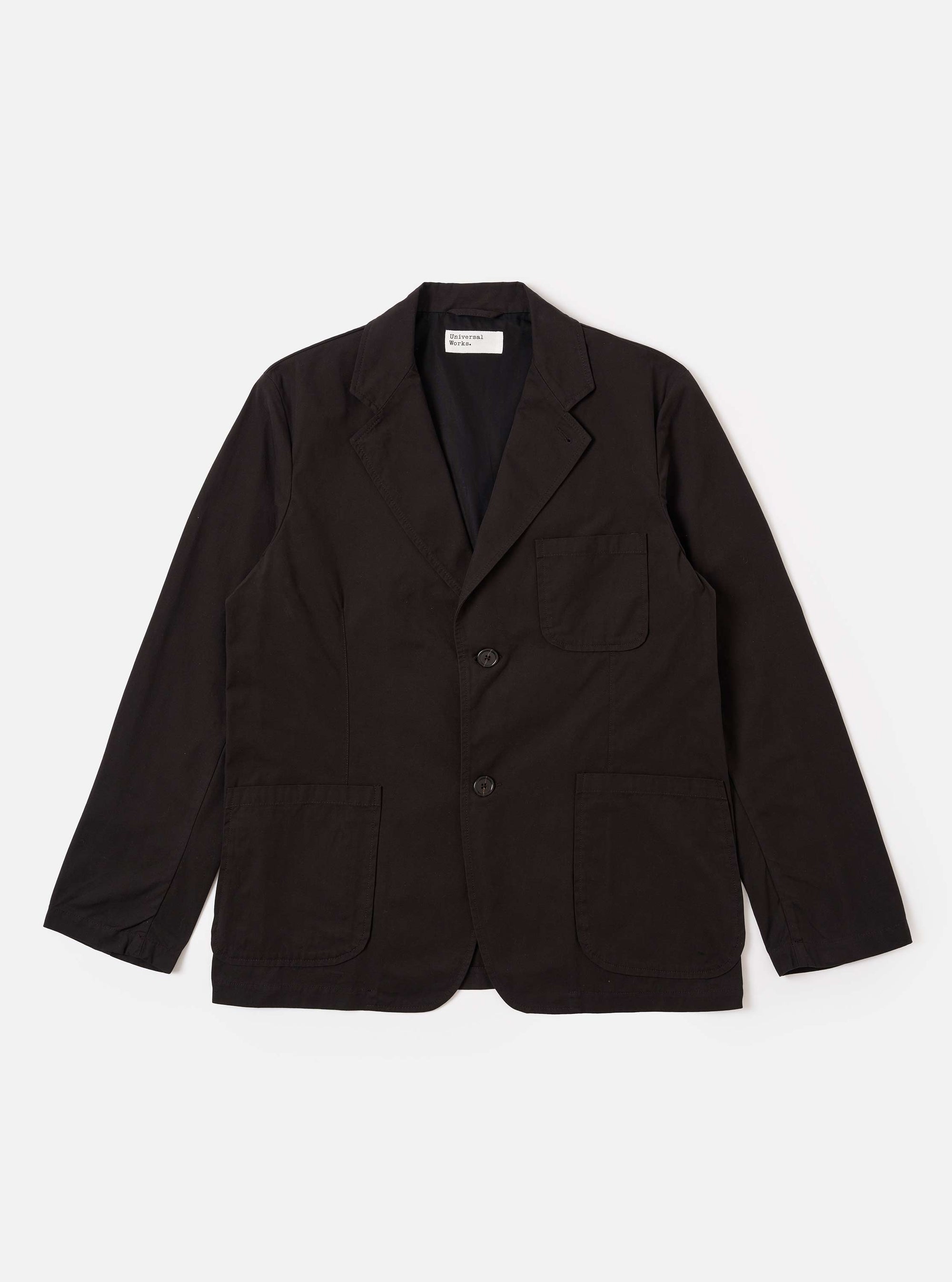 The Licorice Summer Canvas Two Button Jacket is presented as a flat lay against a solid white background. The jacket features a notched lapel, two-button front closure, a single chest patch pocket, and two large patch pockets at the waist. The cotton canvas fabric has a rich brown color and a subtle, textured appearance.