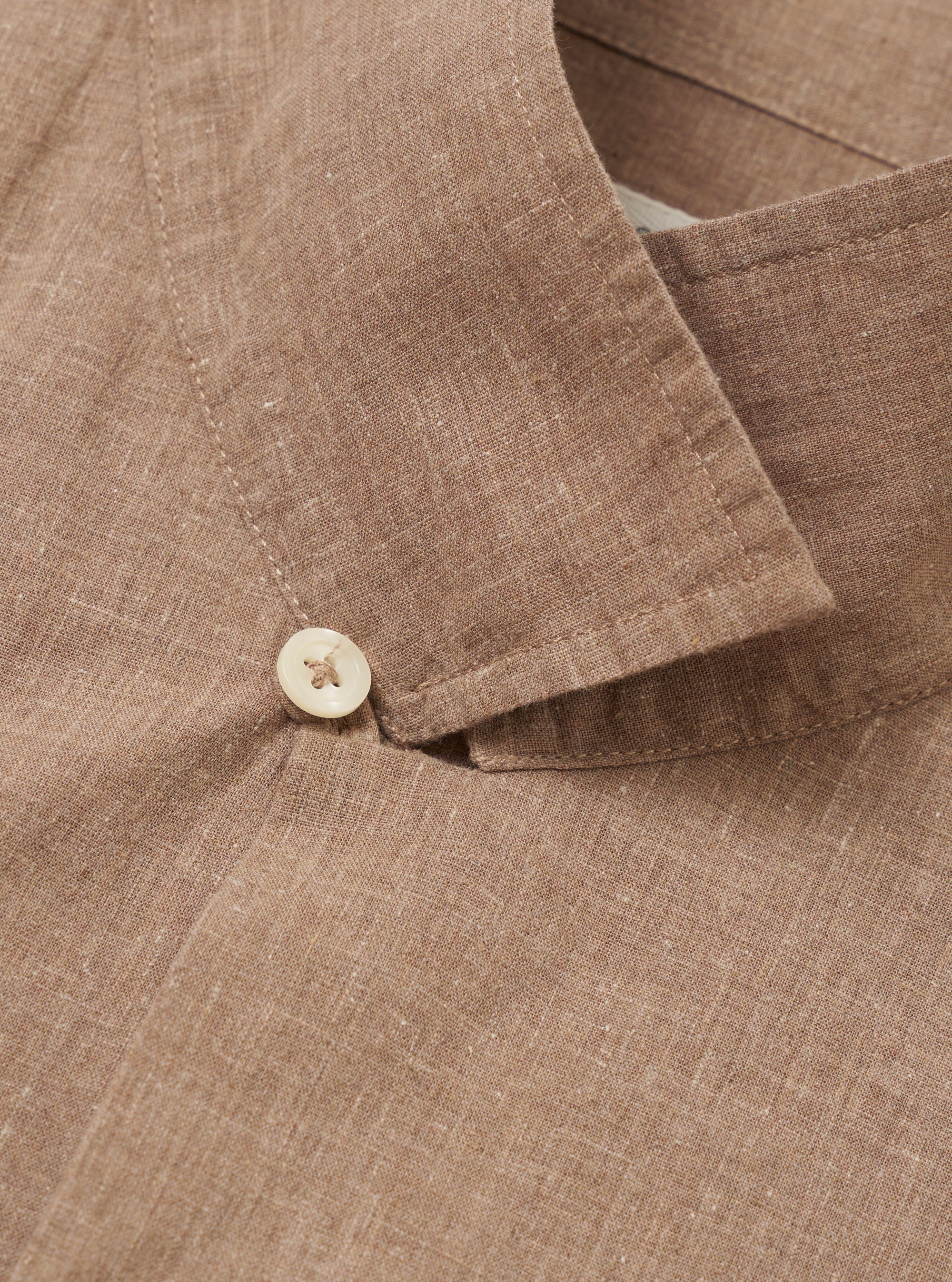 A model is wearing the Brown Sido Linen Mix Road Shirt, shown from the chest down against a plain white background. The shirt is unbuttoned over a white t-shirt, highlighting the camp collar, a single chest patch pocket, and a straight hem. The fabric has a textured linen-cotton weave and a subtle tonal pattern.