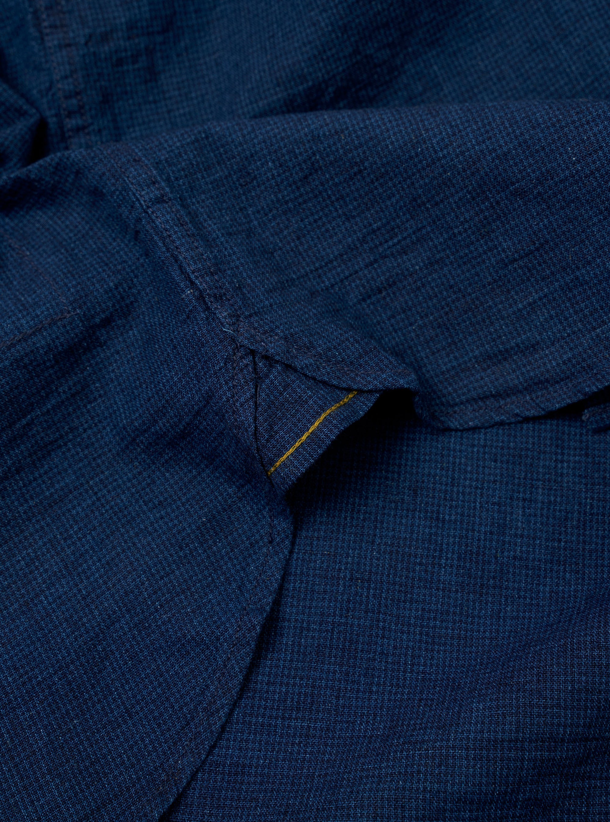 The Indigo Lincot Denim Lazy Day Shirt is shown from a rear angle as a flat lay against a plain white background. The image highlights the back yoke, a central box pleat, and the curved hem of the garment. The fabric is a dark indigo denim with visible stitching details.