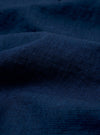 A close-up fabric swatch of the Indigo Lincot Denim Lazy Day Shirt highlights the rich indigo blue color and the distinct diagonal weave of the cotton-linen denim. The image provides a detailed view of the textile's texture and color variations.