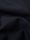 A close-up swatch image of the Navy Tropical Suiting Travail Overshirt fabric displays a deep navy blue color with a fine, smooth weave. The texture of the lightweight tropical wool and polyester blend is clearly visible, highlighting the professional suiting finish.