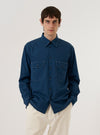 A model wears the Navy Organic Fine Poplin CPO Shirt against a plain, neutral studio background. The shirt features a button-down front, a classic pointed collar, and two prominent chest patch pockets with button-flap closures. The navy organic cotton poplin fabric has a smooth, fine-grained finish. The model is shown in a medium shot, wearing the shirt as an outer layer.