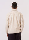 A model wears the Ecru Koko Cotlin Smock Overshirt, shown from a rear three-quarter angle against a plain, neutral background. The pullover-style garment features a relaxed fit, a straight hem, and a simple collar. The ecru fabric exhibits a natural, textured appearance characteristic of a cotton and linen blend.
