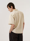 A model wears the Ecru Koko Cotlin S/S Fatigue Shirt, shown from the back against a plain white background. The image highlights the shirt's relaxed fit, short sleeves, and straight hem. The light ecru fabric features a visible textured weave characteristic of the cotton and linen blend. No mannequin is present in the image.