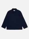 The Indigo Recycled Herringbone Smock Overshirt is shown as a flat lay against a plain white background. The overshirt features a partial button-down placket, a large chest patch pocket on the left side, and a simple collar. The dark indigo fabric has a visible herringbone weave texture.