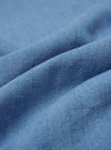 A close-up fabric swatch of the Washed Indigo Recycled Herringbone Road Shirt highlights the intricate herringbone weave pattern. The image showcases the varied blue tones of the washed indigo fabric, providing a detailed view of the textile's texture and color.
