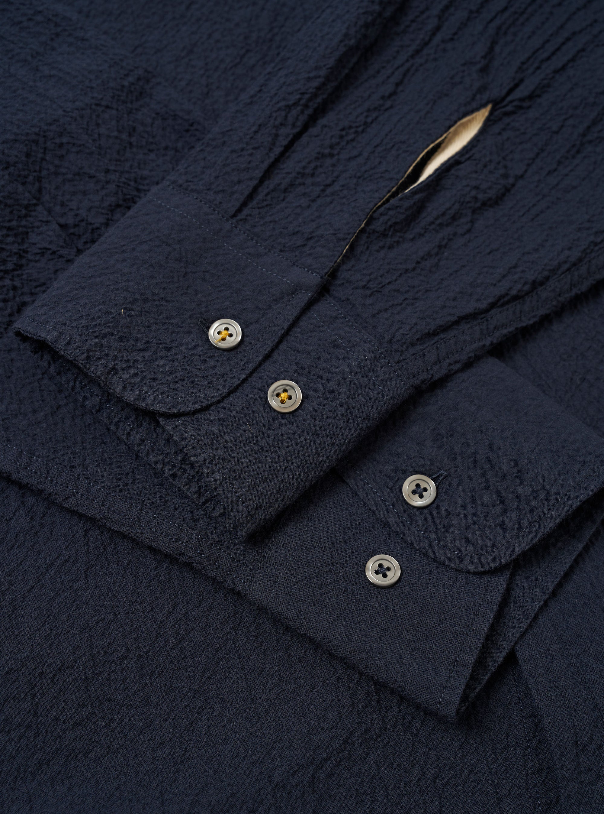 The Navy Seersucker Shirting Lucky Shirt is shown from the back as a flat lay against a plain white background. The image highlights the shirt's straight hem, simple back yoke, and the puckered texture of the navy blue seersucker fabric.