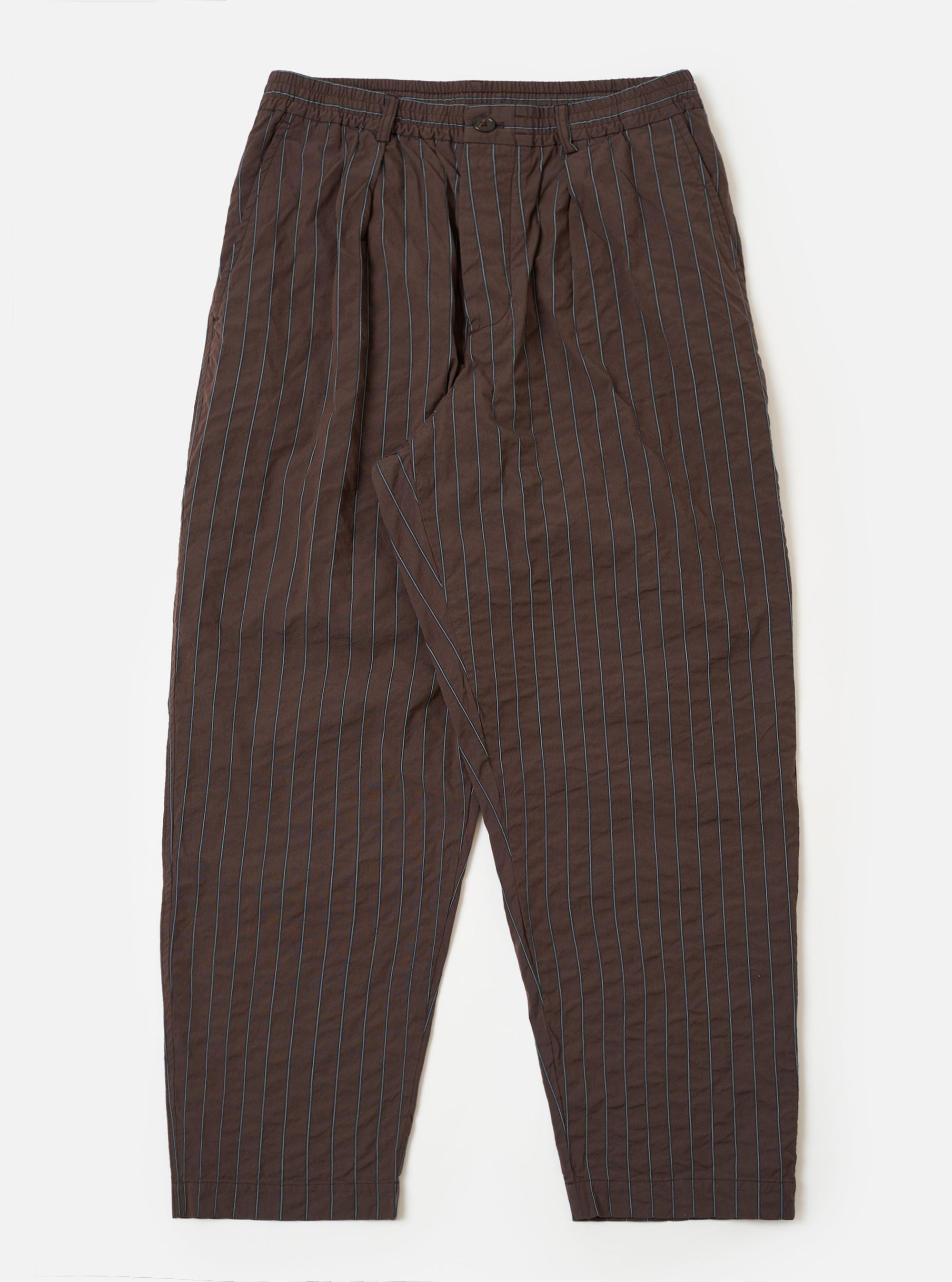 The Brown Chester Stripe Oxford Pant is shown as a flat lay against a plain white background. The trousers feature a loose, wide-leg fit with a pleated front and a comfortable drawstring waistband. The fabric is a brown cotton with a subtle, fine vertical stripe pattern.