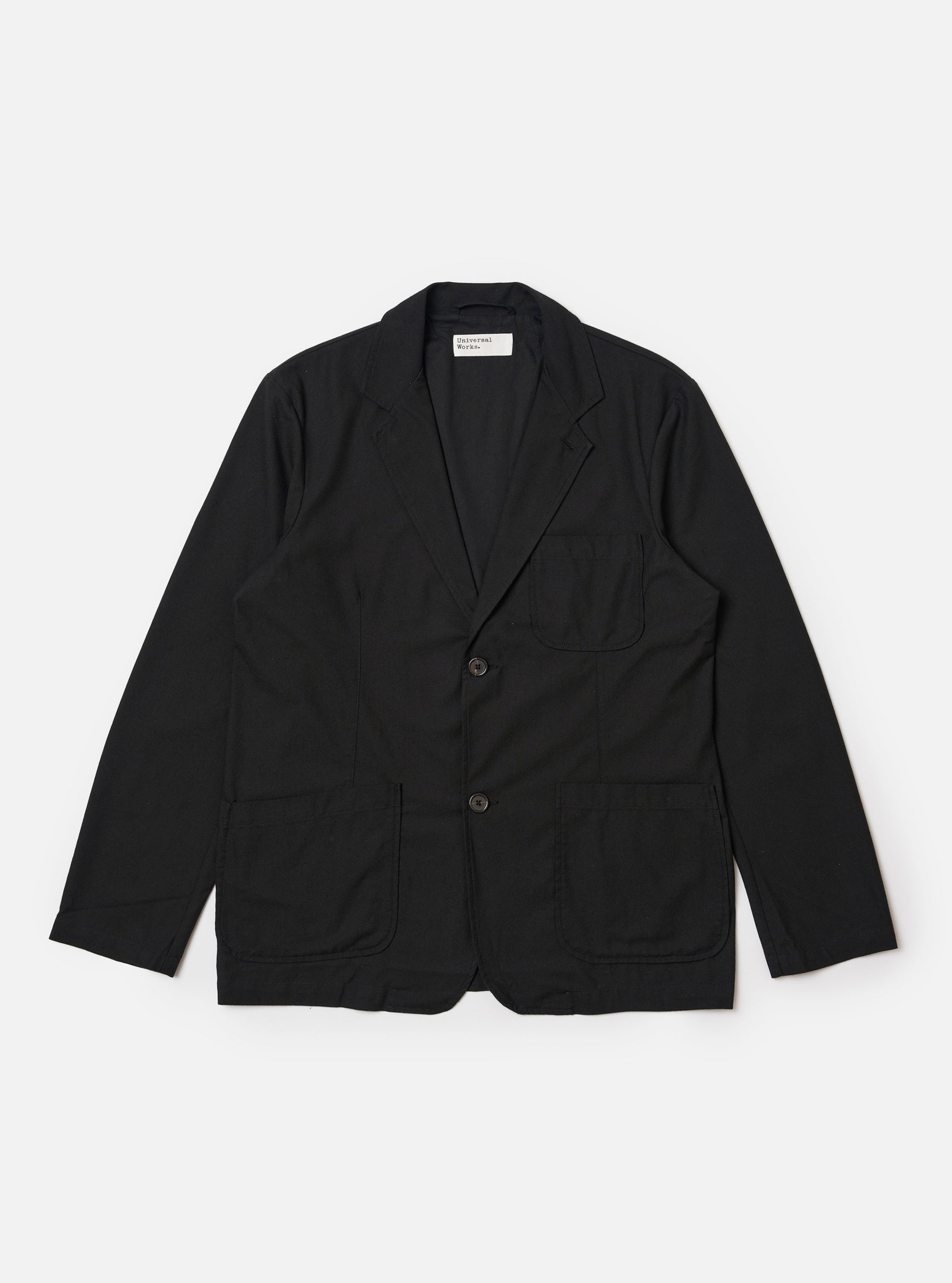 The Black Valencia Cotton Two Button Jacket is shown as a flat lay against a white background. The jacket features a classic notched lapel, a two-button front closure, and three patch pockets, including one at the chest and two larger pockets at the waist. The black cotton-blend fabric has a smooth, clean finish.