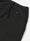 The Black Valencia Cotton Pleated Track Pant is shown from the back as a flat lay against a plain white background. The image highlights the elasticated waistband and two rear pockets: one with a buttoned flap and one buttoned jetted pocket. The black Valencia cotton fabric features a fine, plain weave.