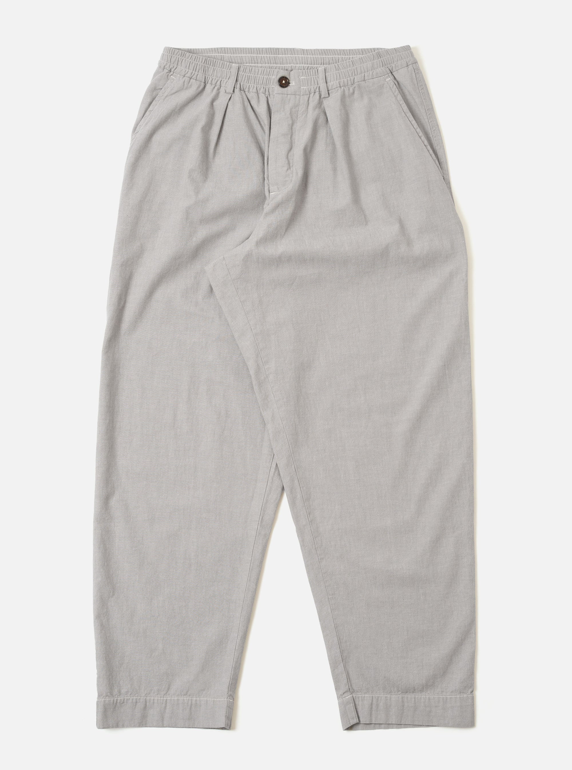 The Grey Izumi Cotton Oxford Pant is shown as a flat lay against a white background. The trousers feature a wide, loose leg with a single pleat at the front and an elasticated waistband with a drawstring. Two front pockets and a button fly are visible. The fabric is a solid grey cotton.