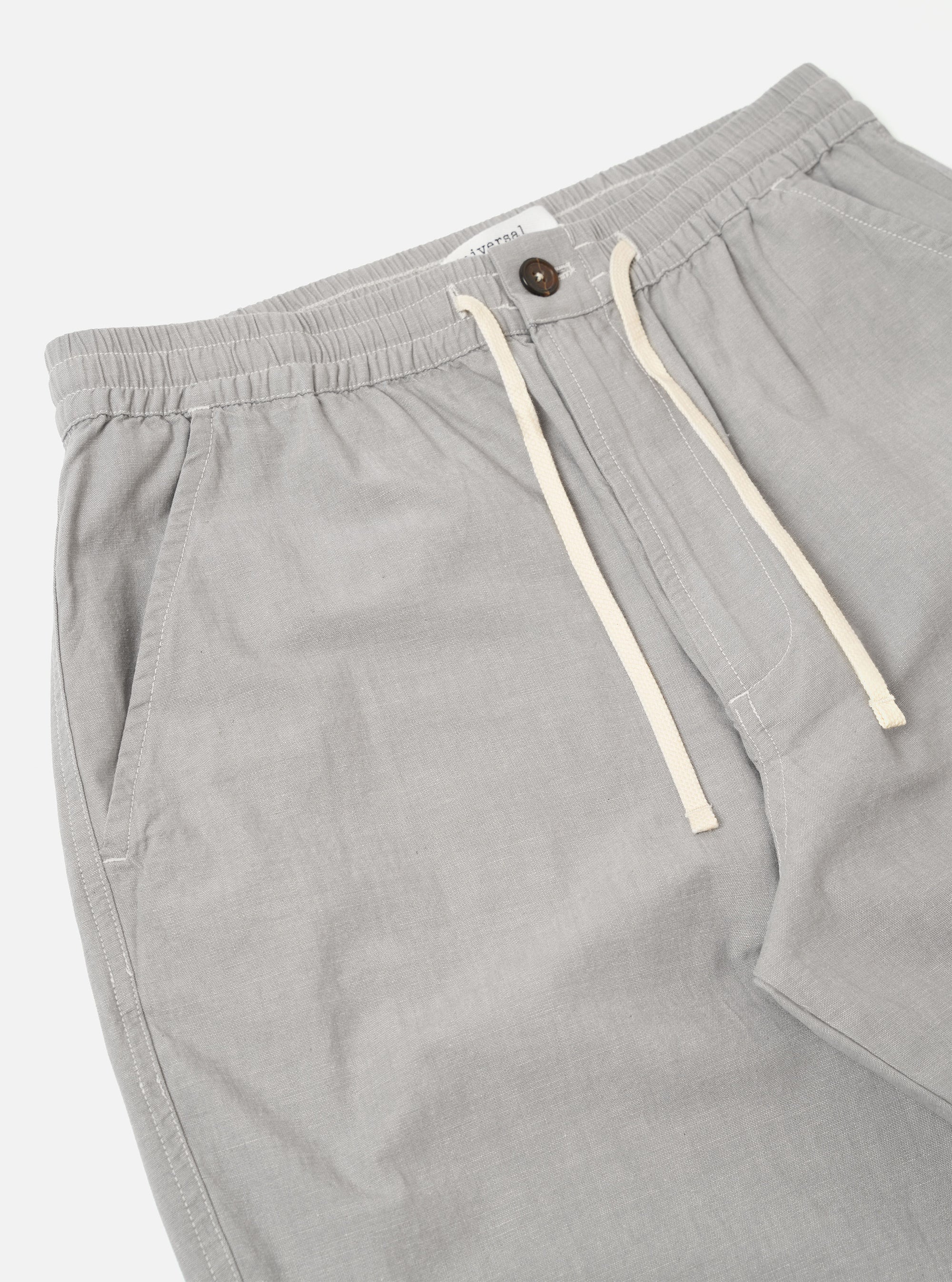 The Grey Izumi Cotton Hi Water Trouser is shown from the back as a flat lay against a plain white background. The trousers feature a drawcord-adjustable waistband and two large rear patch pockets. The garment is made from a grey cotton fabric and has a slightly cropped leg length.