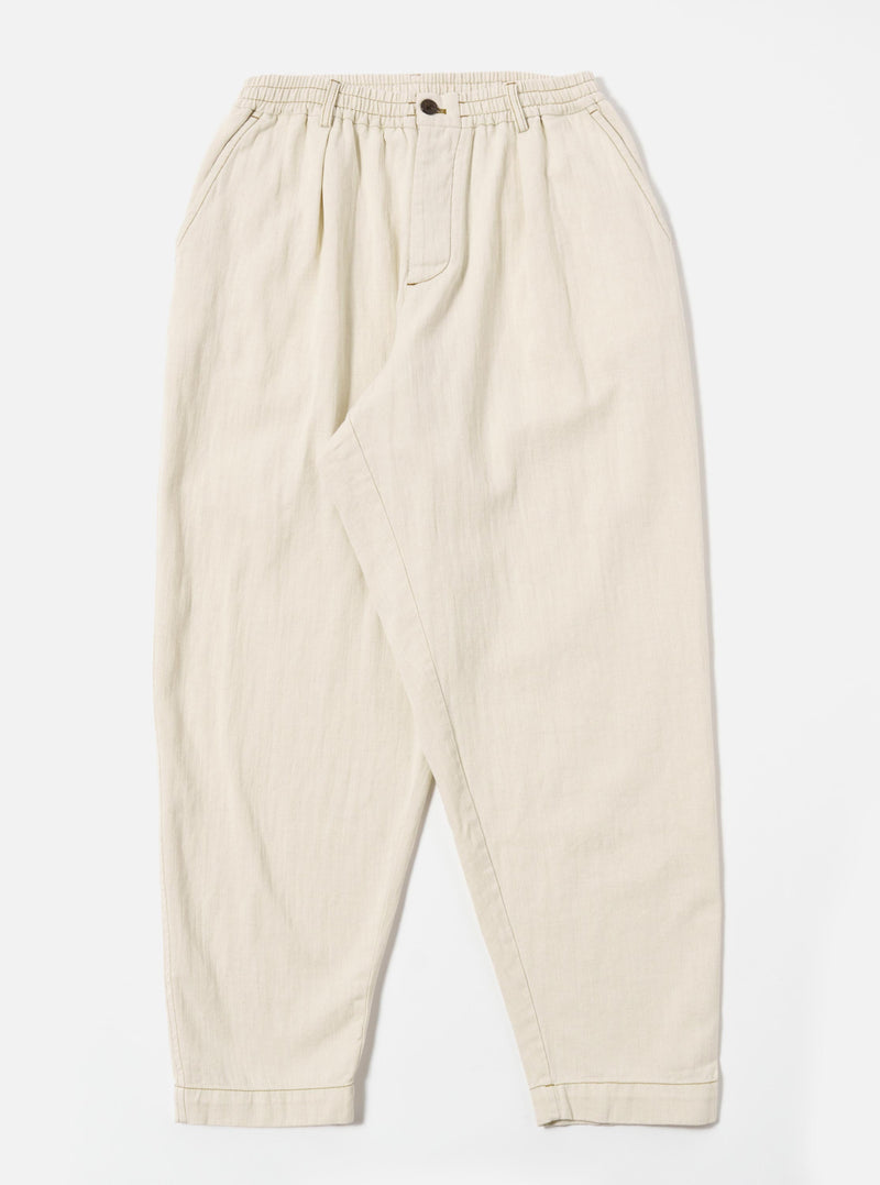 The Ecru Koko Cotlin Pleated Track Pant is shown as a flat lay against a white background. The trousers feature a single pleat at the front, a tapered leg, and an elasticated waistband with a visible drawstring. The light ecru fabric has a textured, slubby appearance.