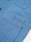 The Washed Indigo Recycled Herringbone Bakers Overshirt is shown from the back as a flat lay against a plain white background. The image highlights the straight hem, the one-piece collar, and the textured herringbone weave of the washed indigo fabric.