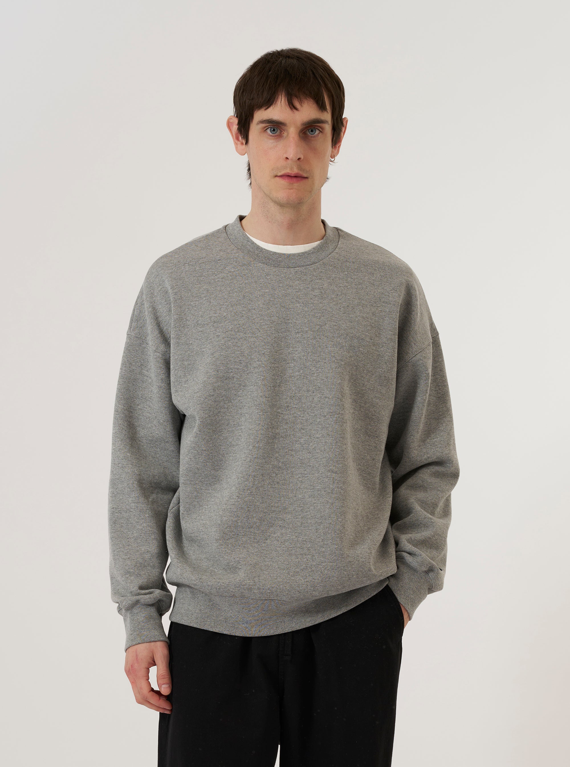 A model wears the Grey Marl Recycled Cotton Blend Jersey Loose Sweatshirt, standing against a plain white background. The sweatshirt features a relaxed, loose fit with a classic crew neckline, dropped shoulders, and ribbed detailing on the cuffs and hem. The recycled cotton blend fabric has a textured grey marl appearance.