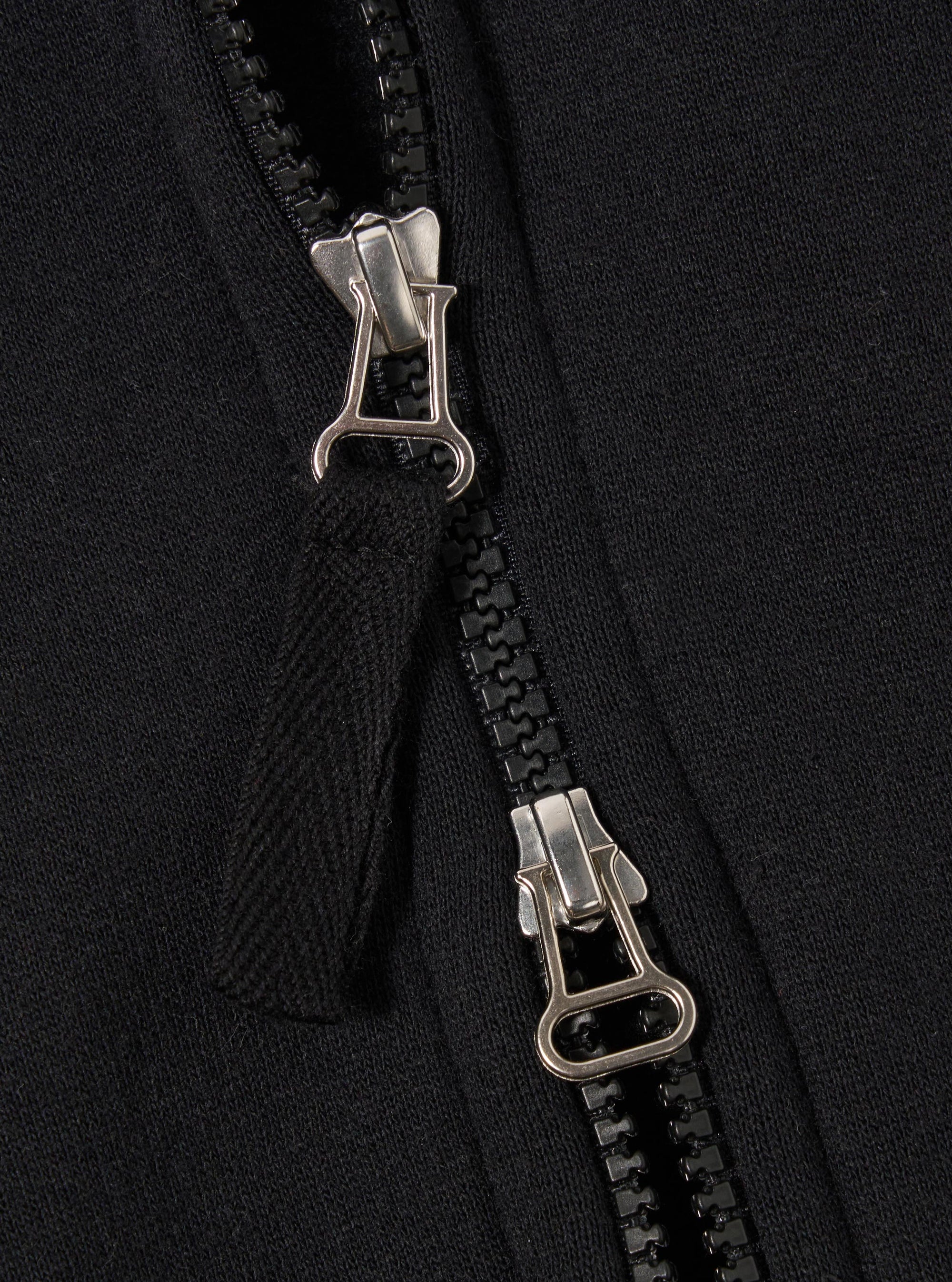 The Black Recycled Cotton Blend Jersey Tyler Jacket is shown in a detail view as a flat lay against a white background. The image highlights the jacket's textured black jersey fabric, a ribbed hem, and a single front patch pocket with a velcro fastening.