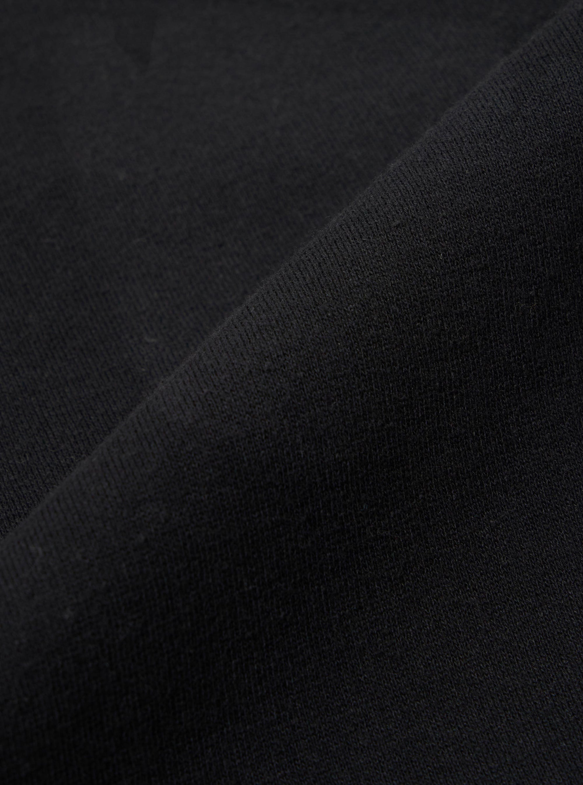A close-up fabric swatch of the Black Recycled Cotton Blend Jersey Tyler Jacket is shown, highlighting the soft texture and fine knit of the black jersey material. The fabric fills the entire frame.
