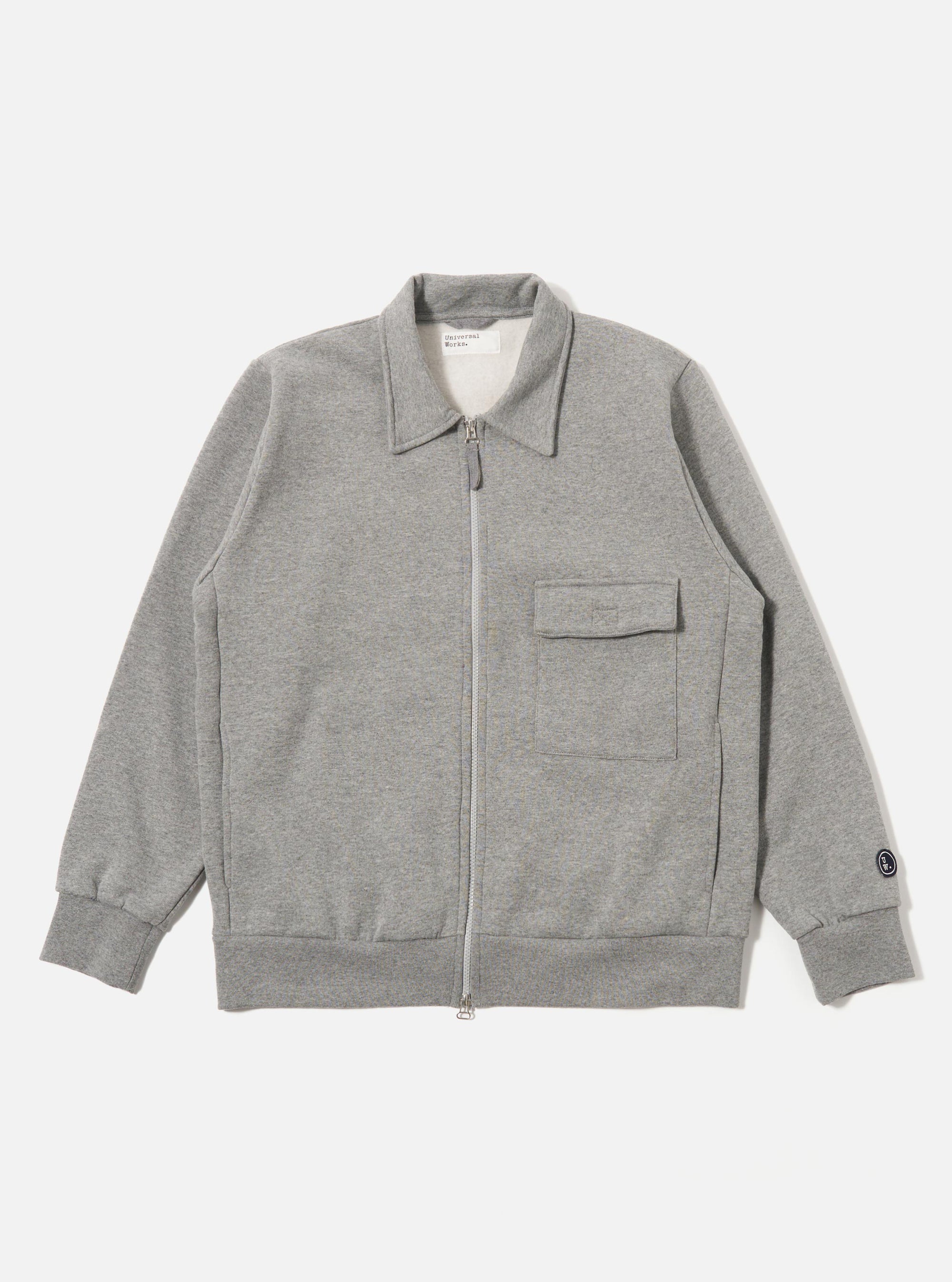 The Grey Marl Recycled Cotton Blend Jersey Tyler Jacket is shown as a flat lay against a white background. The jacket features a self-fabric collar, a two-way central zip closure, and a single chest patch pocket with a velcro fastening. It has ribbed cuffs and a ribbed hem, along with two side seam pockets. The fabric is a textured grey marl jersey.