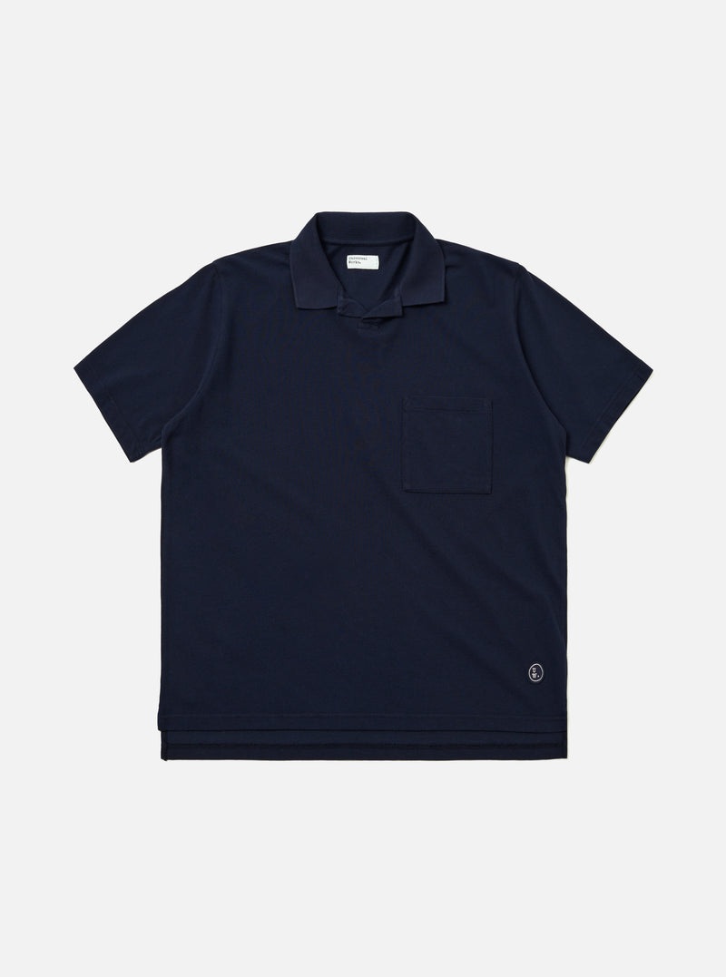The Bright Navy Piquet Vacation Polo is shown as a flat lay against a white background. The polo features a buttonless open collar, a single patch pocket on the left chest, and a straight hem. The bright navy cotton fabric has a visible textured piquet weave.