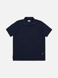 The Bright Navy Piquet Vacation Polo is shown as a flat lay against a white background. The polo features a buttonless open collar, a single patch pocket on the left chest, and a straight hem. The bright navy cotton fabric has a visible textured piquet weave.