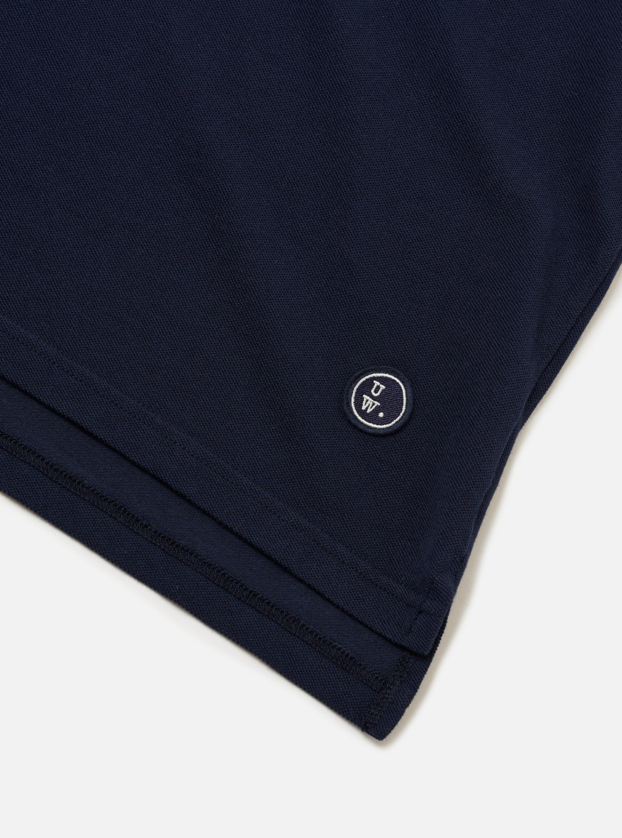 The Bright Navy Piquet Vacation Polo is shown as a flat lay against a white background. The polo features a one-piece open collar, a single chest patch pocket, and short sleeves. The piquet fabric has a subtle textured weave.