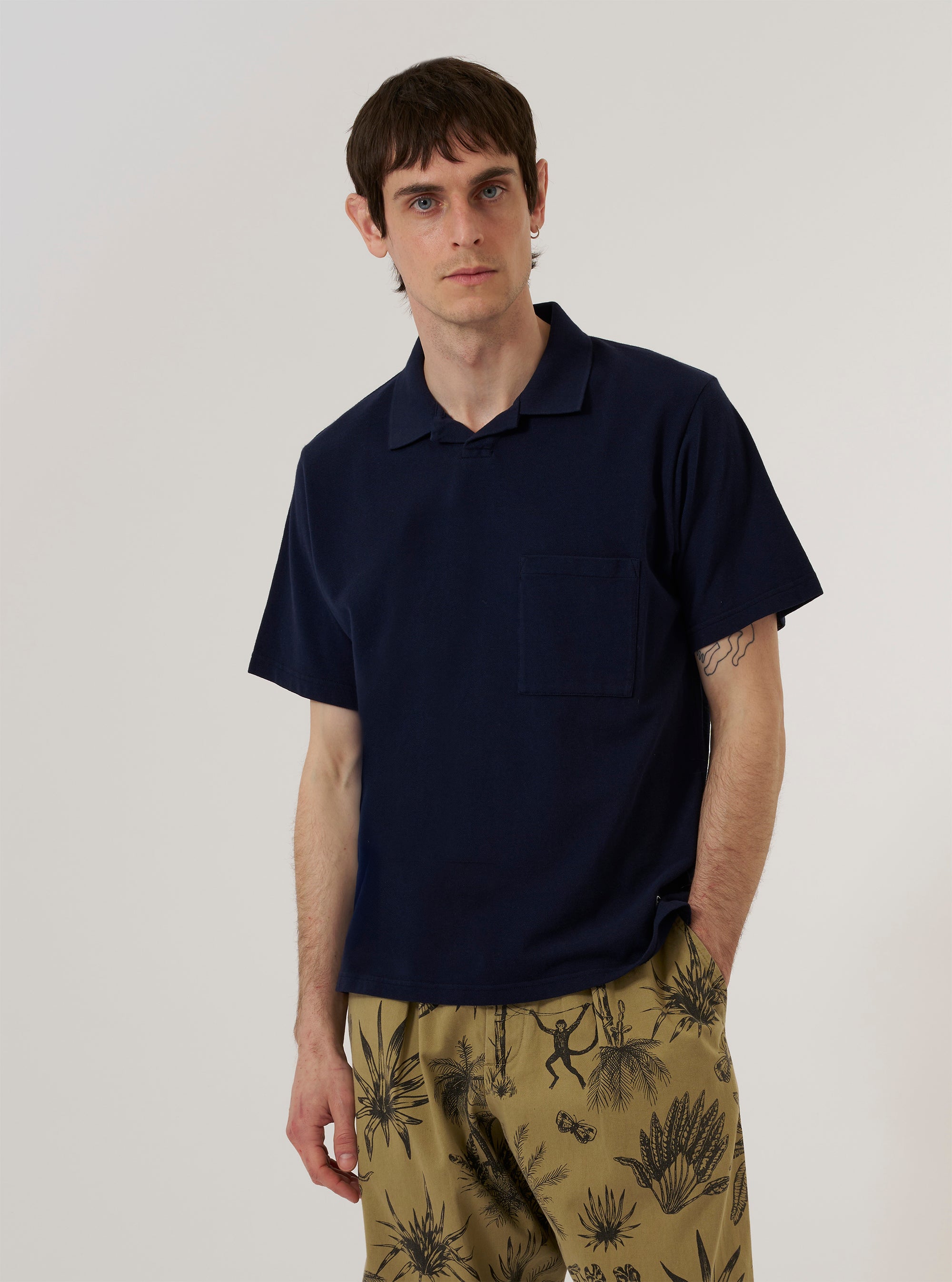 A model wears the Bright Navy Piquet Vacation Polo against a plain, light grey background. The polo features a textured piqué cotton fabric, a relaxed vacation-style spread collar, and a short three-button placket. The model is shown from the waist up, facing forward, with the garment exhibiting a structured yet comfortable fit.