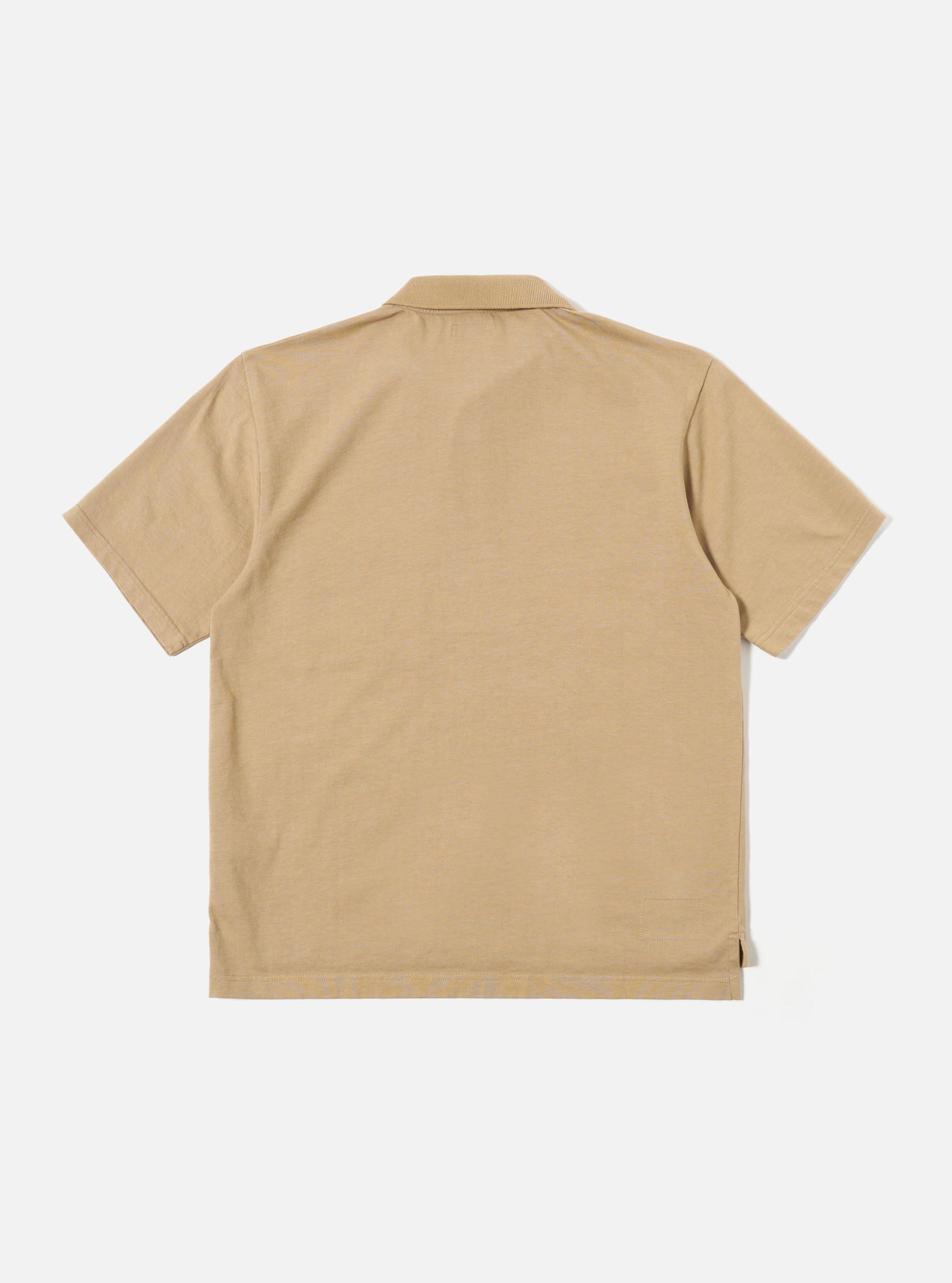 The Sand Rugby Jersey Oversized Vacation Polo is shown from the back as a flat lay against a plain white background. The polo features an oversized silhouette with dropped shoulders and short sleeves. The image highlights the smooth, solid sand-colored jersey fabric and clean stitching at the hem.