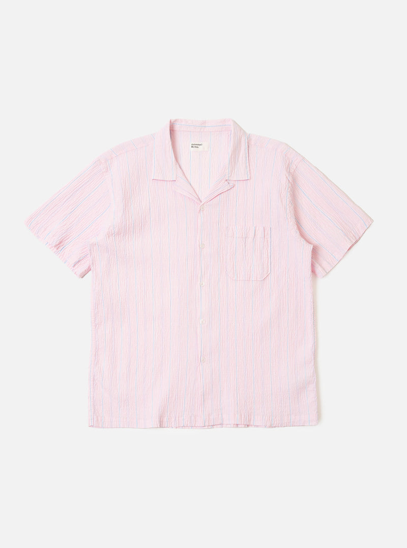 The Pink Lily Stripe Road Shirt is shown as a flat lay against a white background. The short-sleeve shirt features a pink and white vertical pinstripe pattern, a single chest patch pocket on the left side, and a straight hem. The camp collar is open-necked with a visible loop closure at the top. The fabric has a fine seersucker texture.