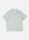 The Green Seersucker Road Shirt is shown as a flat lay against a white background. The shirt features a camp collar, a button-front closure with tonal buttons, and a straight hem. The fabric has a distinctive puckered seersucker texture in a solid green color.