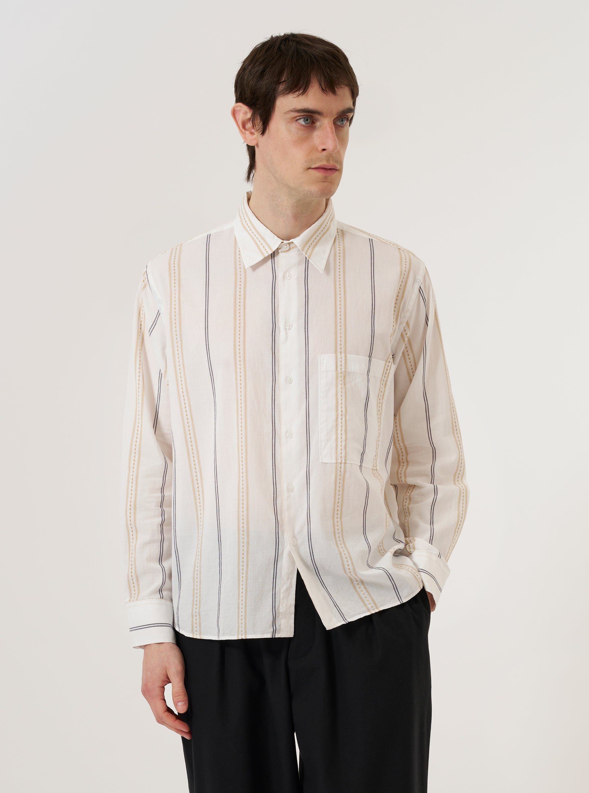 A model wears the Ecru/Navy/Sand Hendrix Stripe Square Pocket Shirt over a dark t-shirt against a plain white background. The shirt features a vertical multi-colored stripe pattern in ecru, navy, and sand, with two large square patch pockets on the chest and a classic button-down front. The model is shown from the chest up with the shirt worn open and the collar slightly raised.