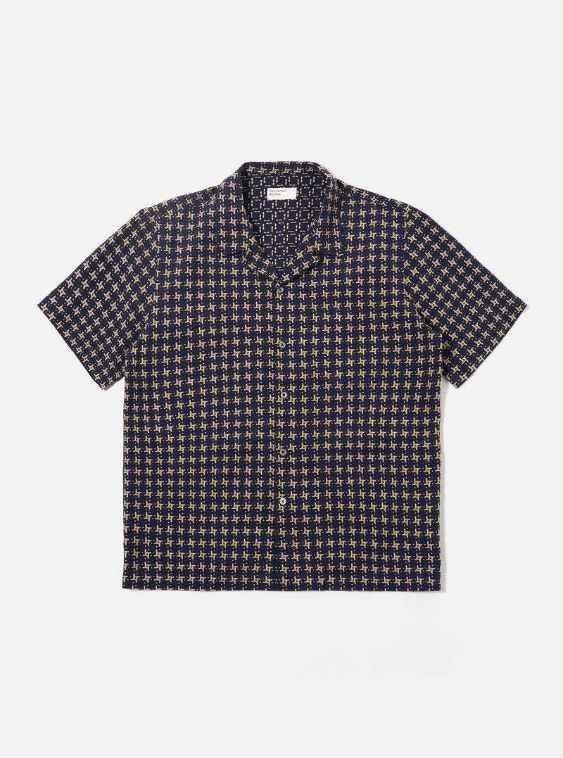 The Navy/Sand Rhodes 8 Cotton Road Shirt is shown as a flat lay against a white background. The shirt features a relaxed camp collar, a central button-down front, and short sleeves. The fabric is decorated with a patterned design in navy and sand colors.