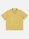 The Yellow Mykonos Cotton Road Shirt is shown as a flat lay against a white background. The shirt features a camp collar, a button-down front, and a single chest pocket. The fabric is decorated with a patterned design in shades of yellow and ochre.