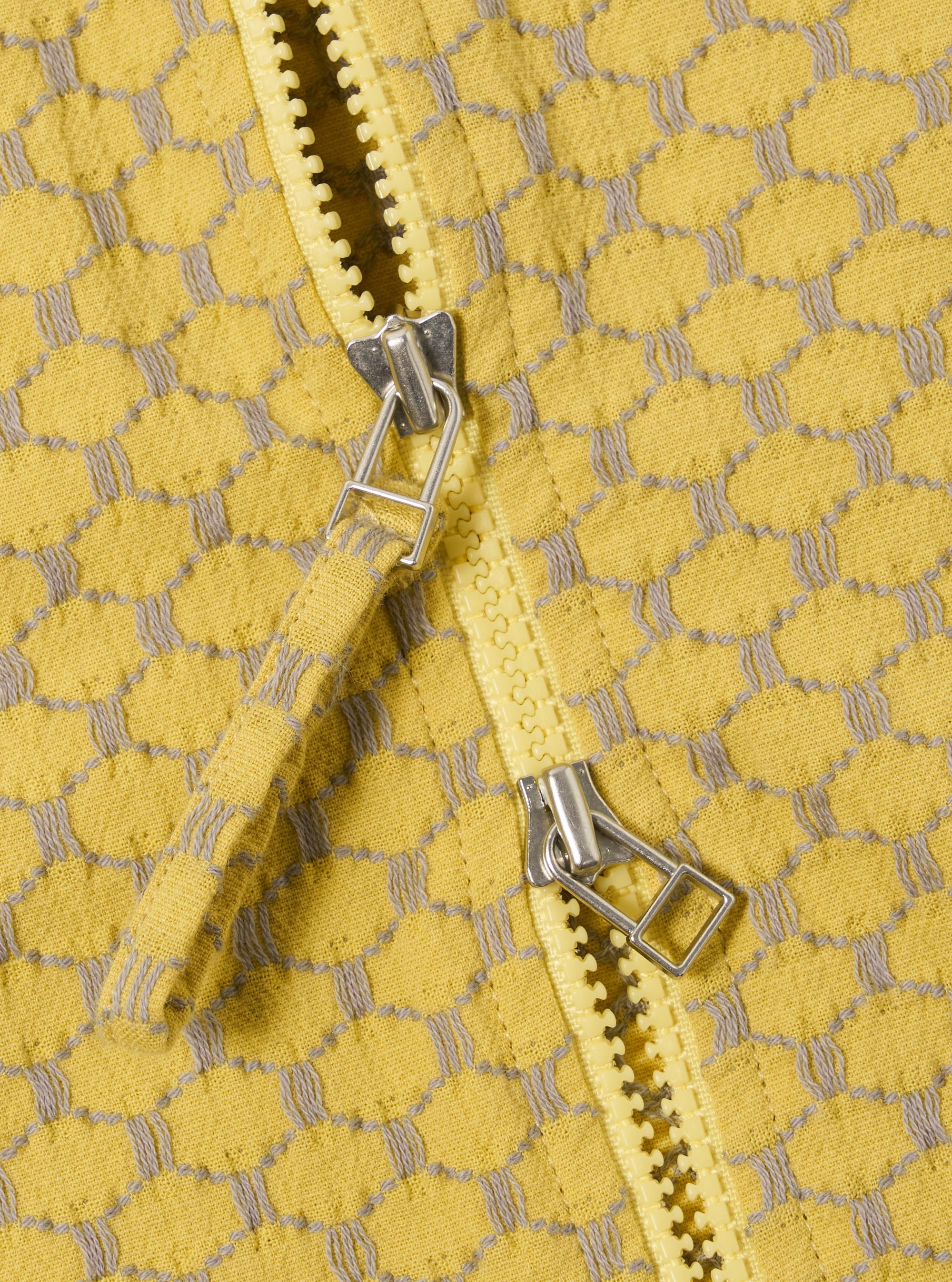 The Yellow Mykonos Cotton Zip Shirt is shown in a detail view as a flat lay against a plain white background. The image highlights the textured weave of the yellow cotton fabric and the metal zip-front closure.