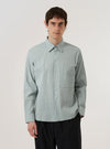 A model wears the Green Seersucker Square Pocket Shirt against a plain white background. The shirt features a button-down front, a classic collar, and two large square patch pockets on the chest. The fabric has a distinct puckered seersucker texture in a solid green color. The model is shown from the chest up, wearing the shirt buttoned.