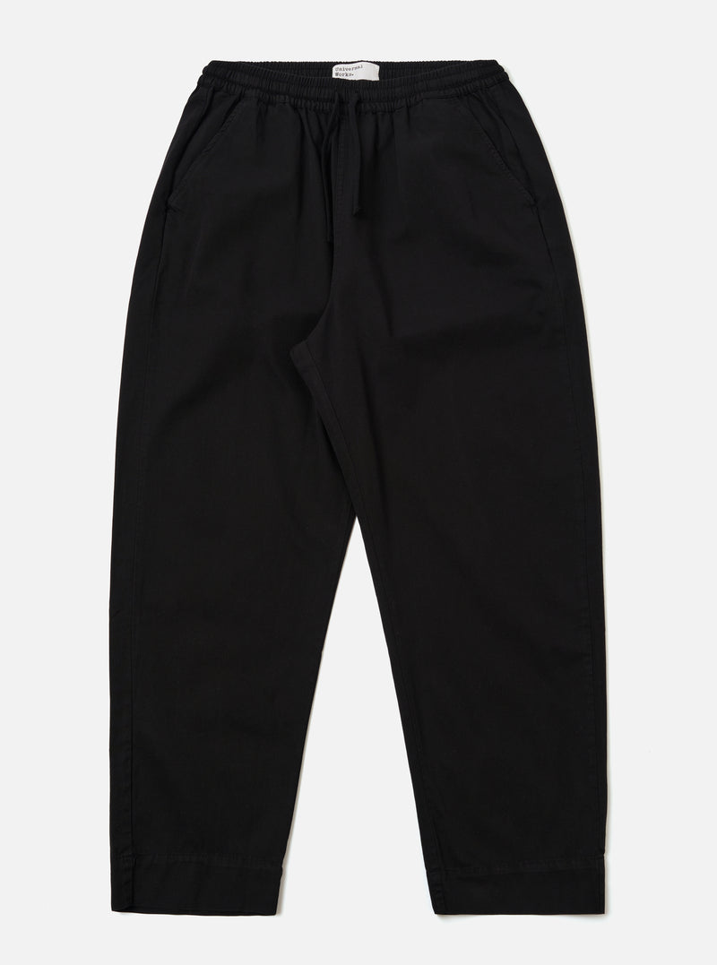 The Black Kelly Cotton Judo Pant is shown as a flat lay against a plain white background. The trousers feature a straight, wide-leg silhouette with an elasticated waistband and a visible tonal drawstring. Two side pockets are prominent at the hips. The fabric appears sturdy with a smooth finish.