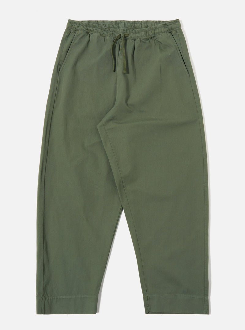 The Olive Kelly Cotton Judo Pant is shown as a flat lay against a plain white background. The trousers feature a wide, straight-leg silhouette, an elasticated waistband with an external drawstring, and two large patch pockets on the front. The fabric is a solid olive green cotton with a visible textured weave.