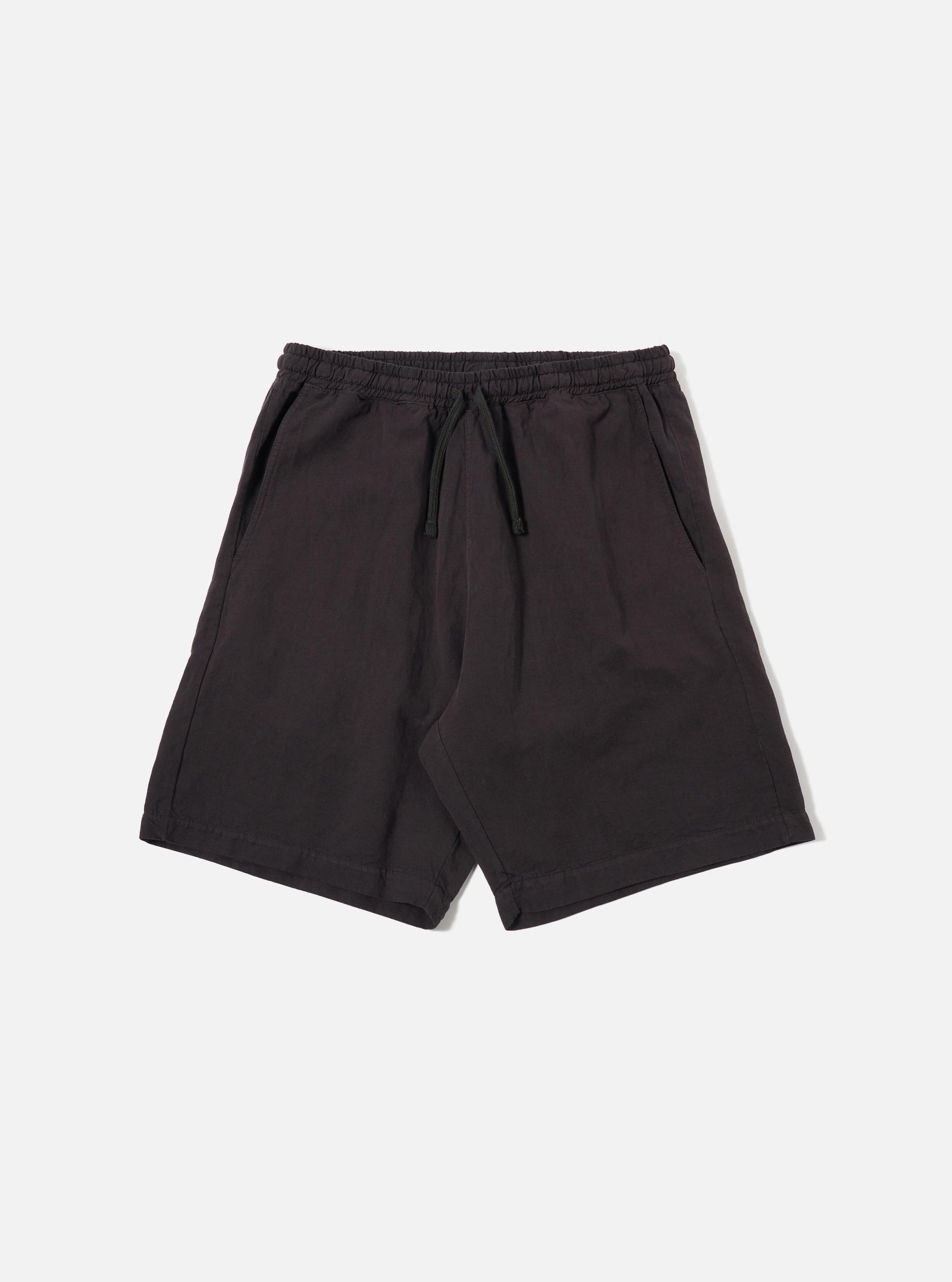 The Licorice Lyo Linen Mix Simple Short is presented as a flat lay against a plain white background. The shorts feature an elasticated waistband with a matching drawstring, slanted side pockets, and a clean, straight-leg silhouette. The fabric has a subtle, natural texture characteristic of a linen blend.
