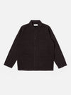 The Licorice Lyo Linen Mix Coverall Jacket is shown as a flat lay against a white background. The jacket features a full collar, a button-down front, and three large square patch pockets on the front, with an additional small pen pocket located on the sleeve. The garment is made from a brown lyo-linen mix fabric and has a short, square fit with simple cuffs.